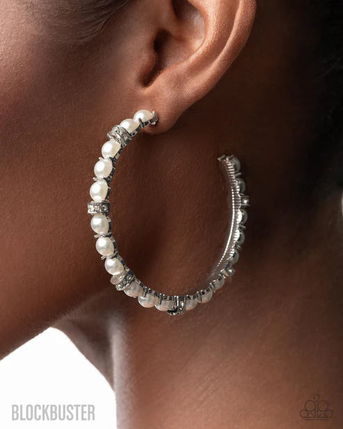Silver hoop earrings with pearls worn by a person