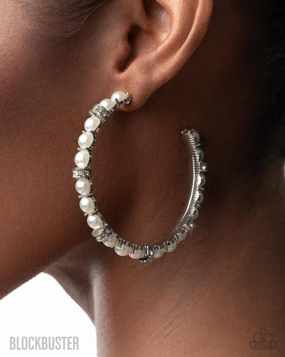 Silver hoop earrings with pearls worn by a person