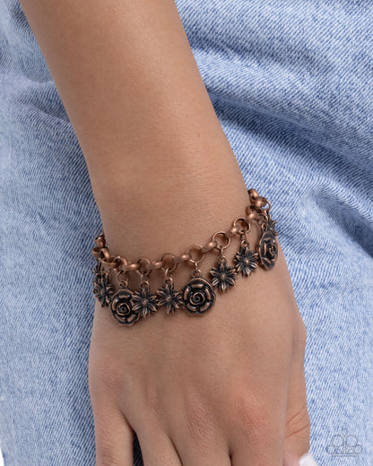Bracelet with floral designs on a wrist against a blue fabric background