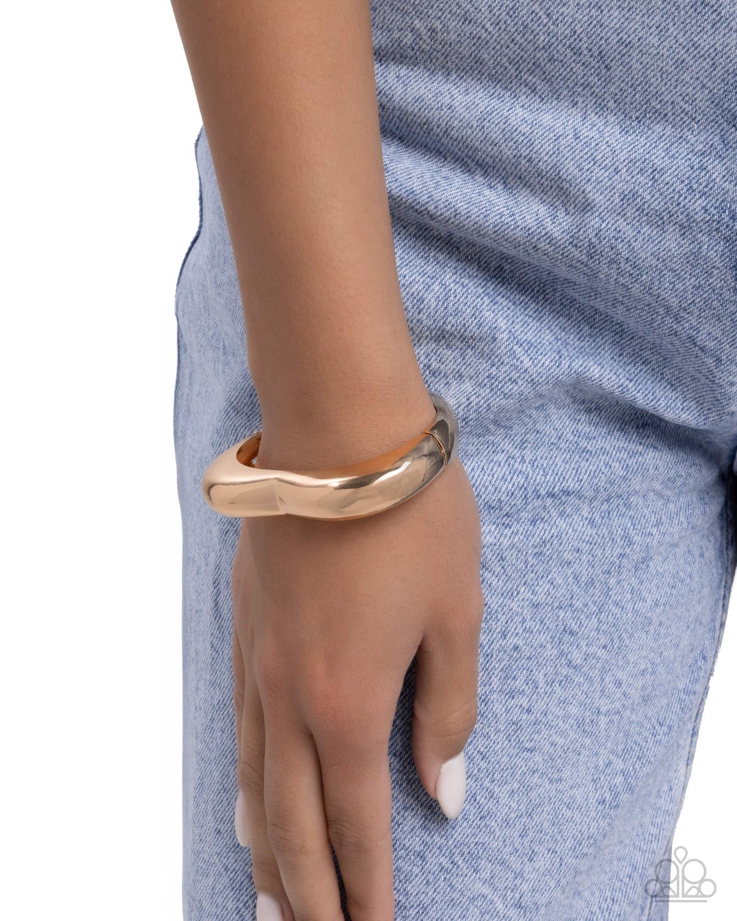 Gold bracelet on a wrist with a blue denim background