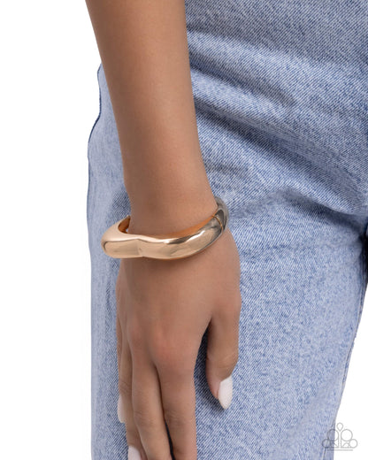 Gold bracelet on a wrist with a blue denim background