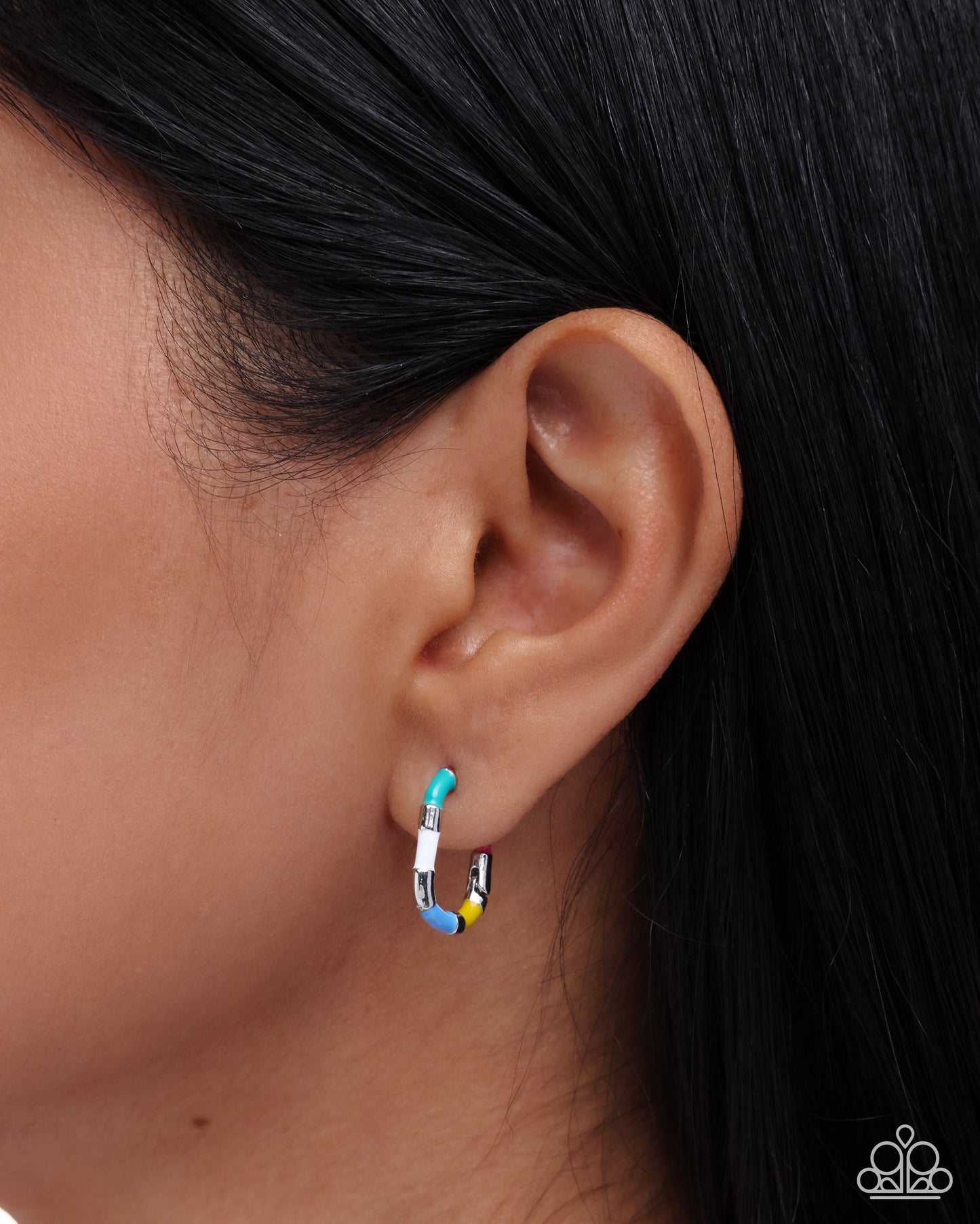 Close-up of an ear wearing a colorful hoop earring with a dark background