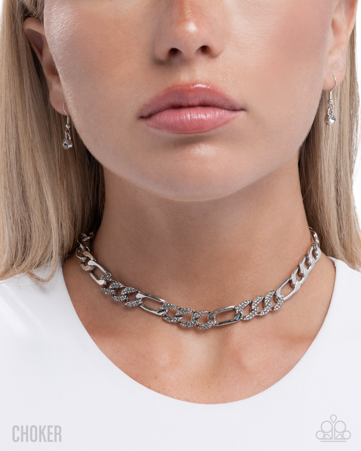Close-up of a person wearing a silver chain choker necklace with earrings.