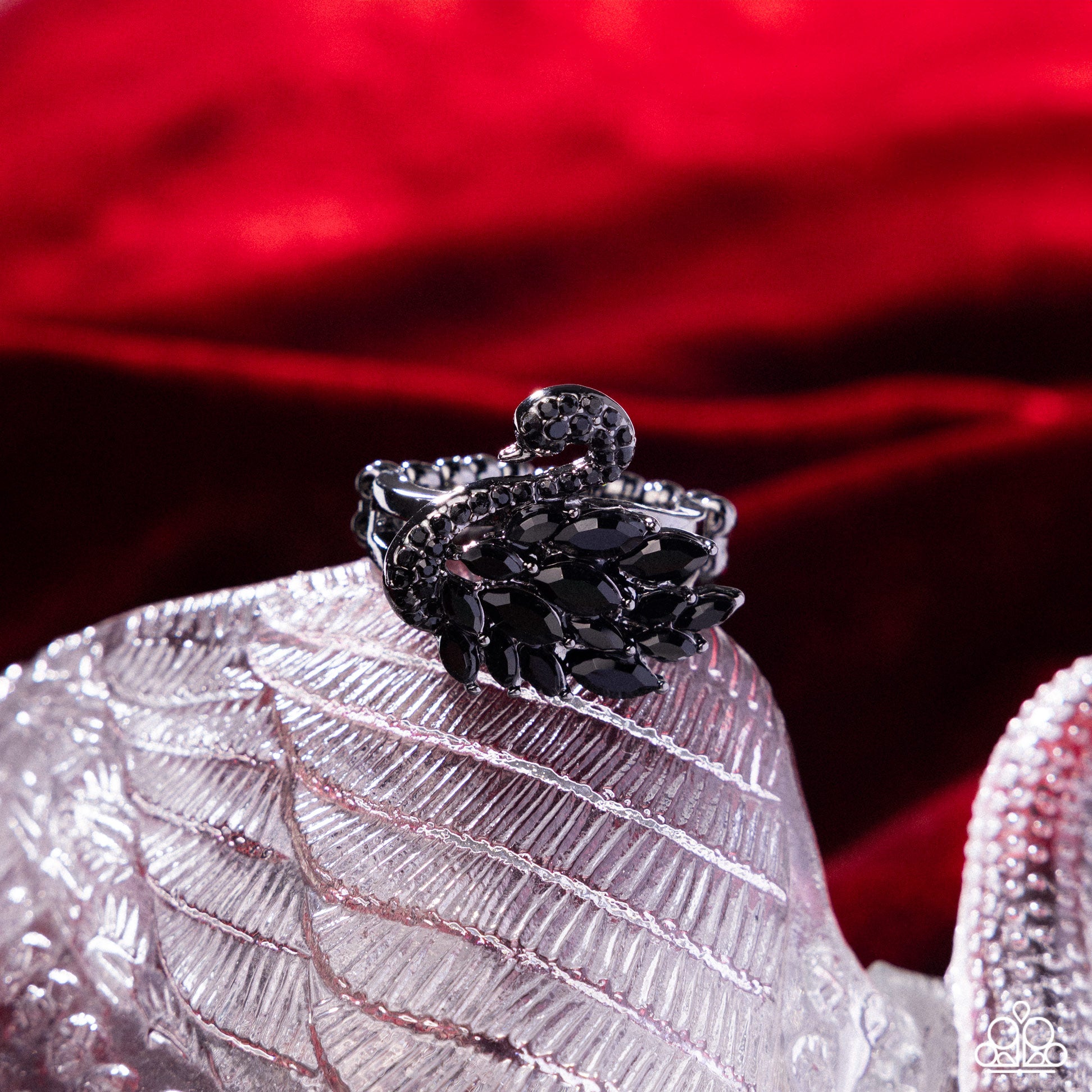 Black ring on a textured white surface with a red fabric background