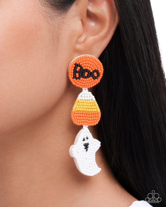 Halloween-themed earrings with candy corn and ghost design on a blurred background
