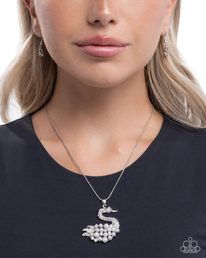 Woman wearing a silver swan pendant necklace on a plain background