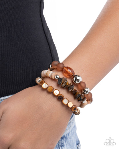 Stack of beaded bracelets on a wrist with a plain background