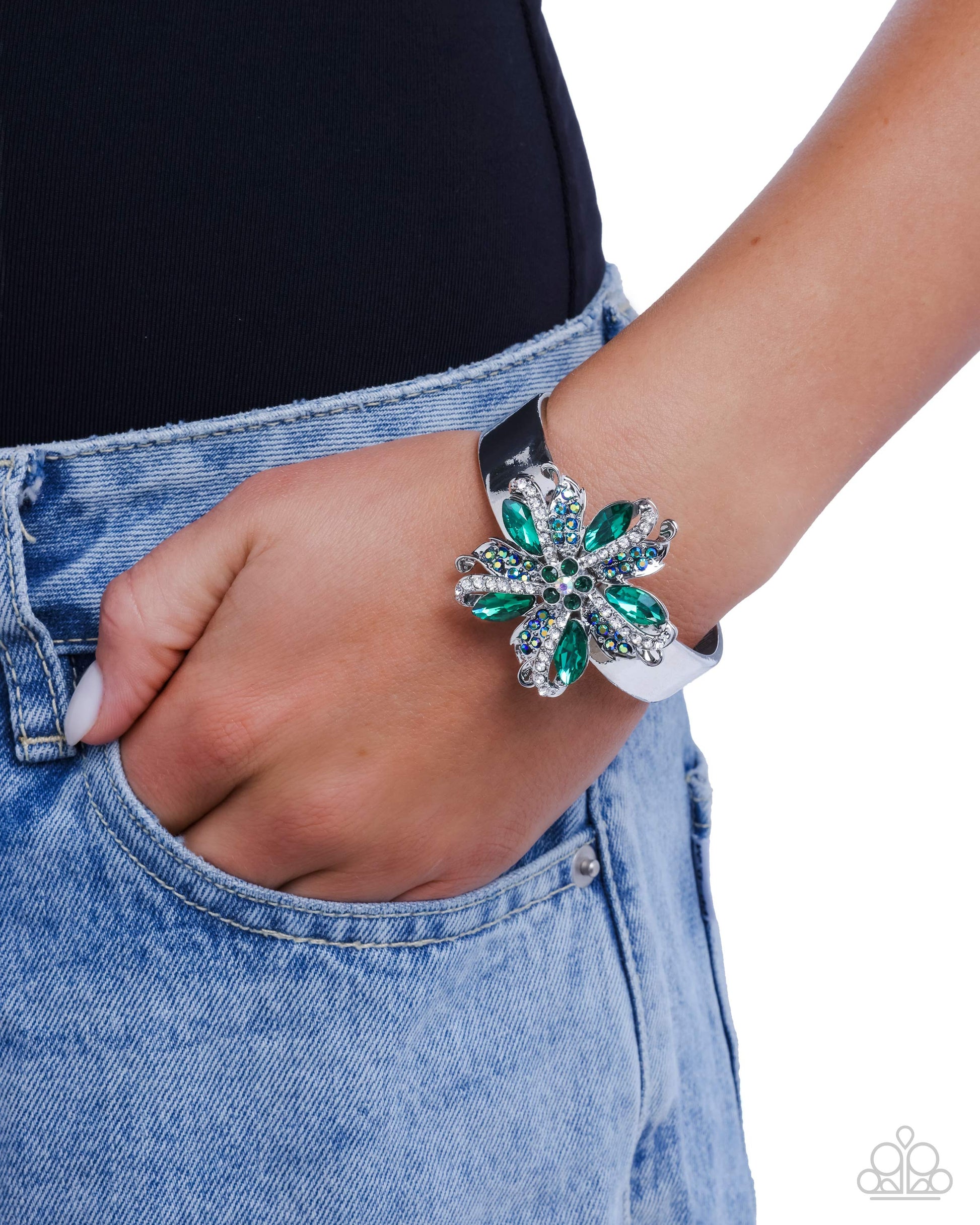 Close-up of a hand wearing a decorative bracelet with green and silver elements, against a white background.