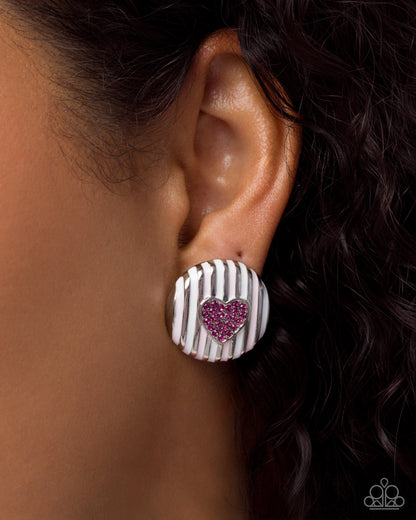 Earring with pink heart design on a blurred background