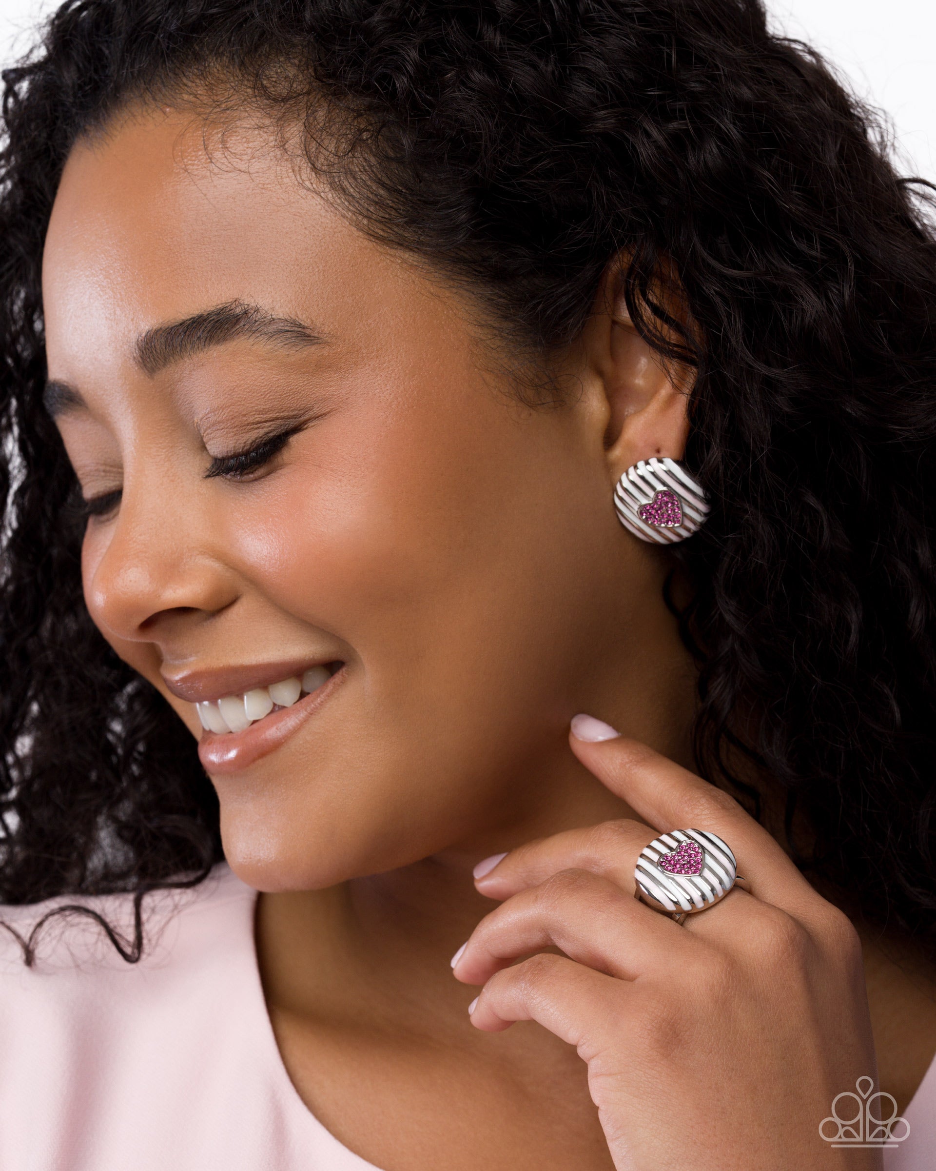 Woman wearing silver earrings and ring with pink gemstones on a white background