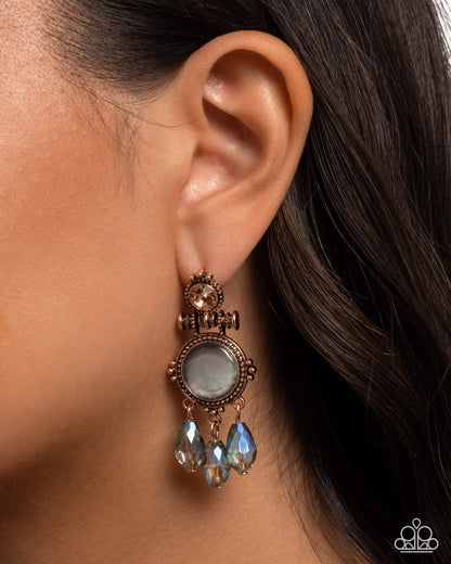 Close-up of an ear wearing a decorative earring with a stone and dangling beads.