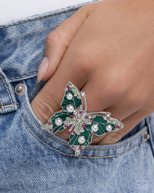 Butterfly-shaped brooch with pearls and gemstones on a denim background
