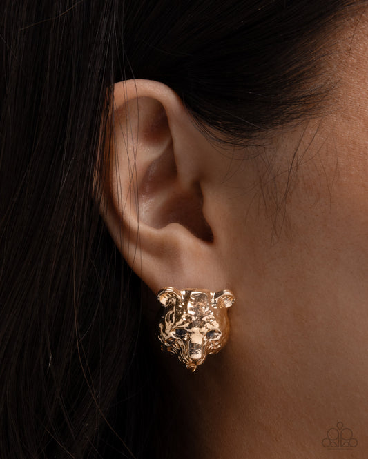 Gold lion head earring worn on an ear with dark hair.