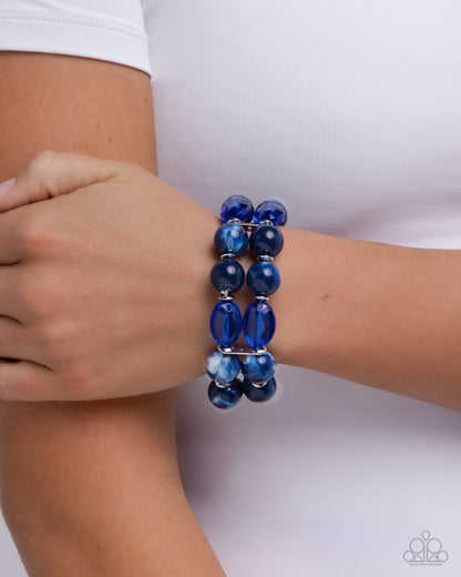 Blue beaded bracelet on a wrist against a white background