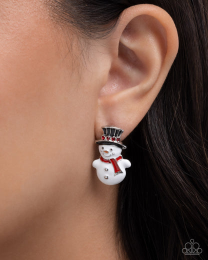 Snowman earring worn on an ear with a blurred background