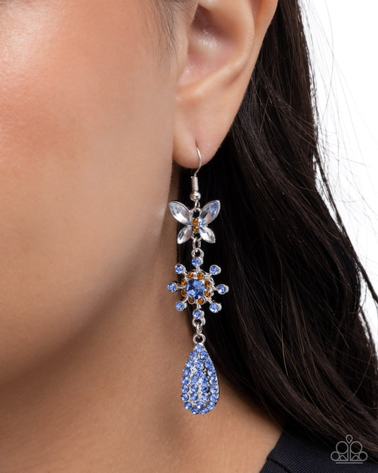 Close-up of a person wearing a blue teardrop earring with floral design.