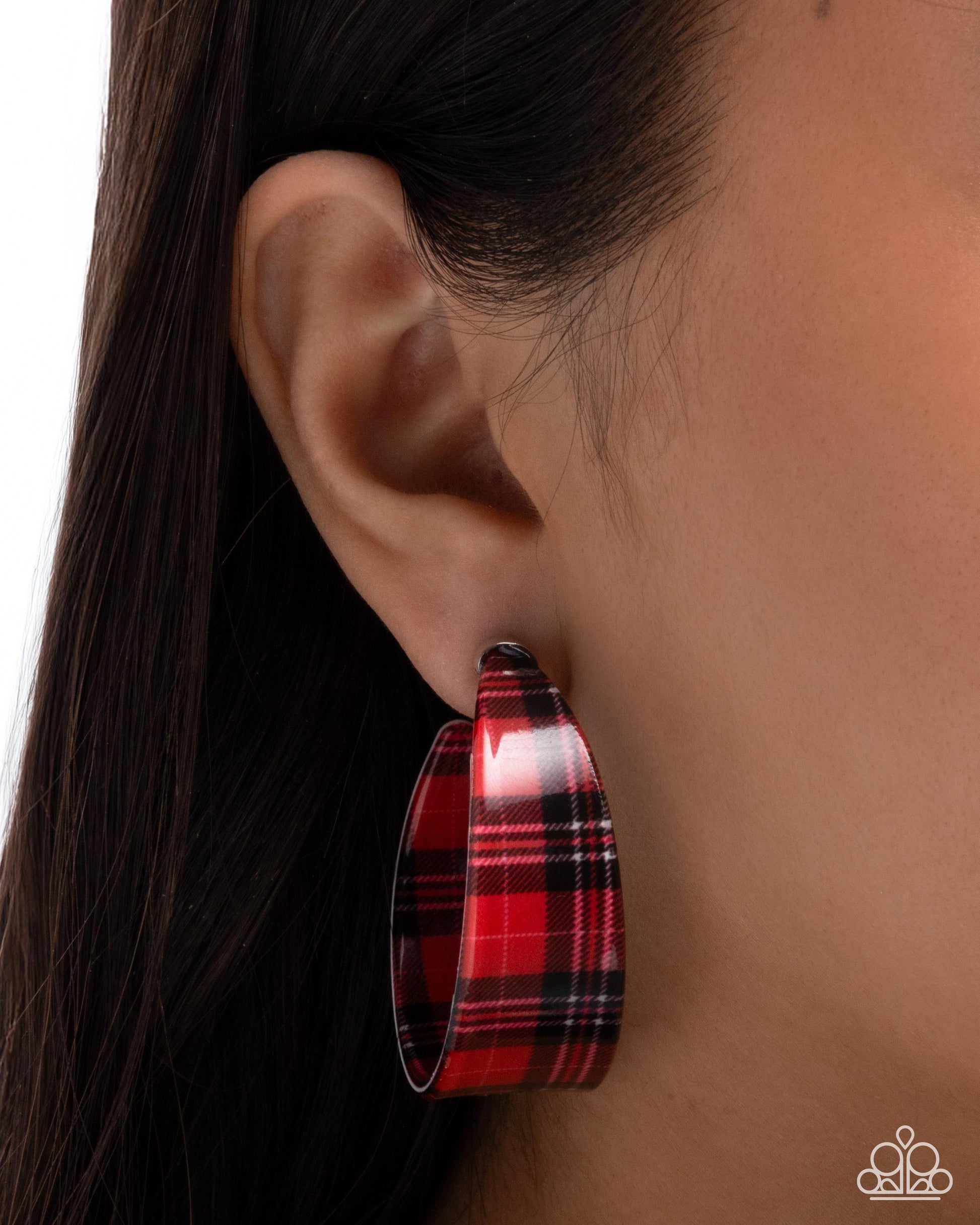 Red plaid hoop earring worn by a person with dark hair.