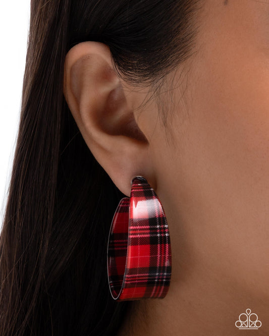 Red plaid hoop earring worn by a person with dark hair.