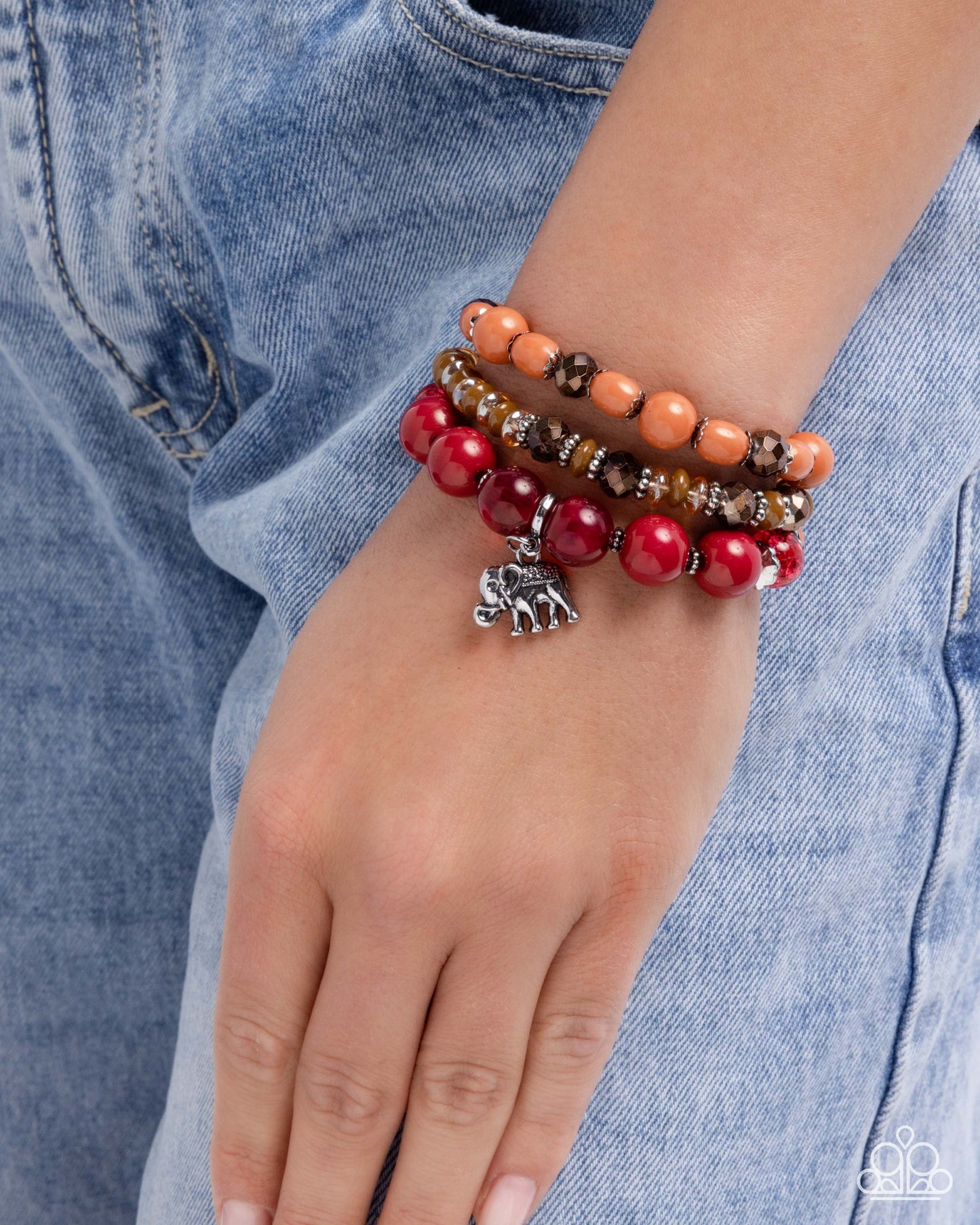 Stack of colorful beaded bracelets on a wrist with a denim background