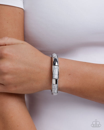 Silver bracelet on a wrist with a white background