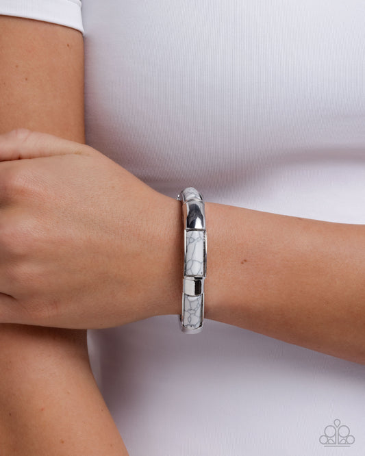 Silver bracelet on a wrist with a white background