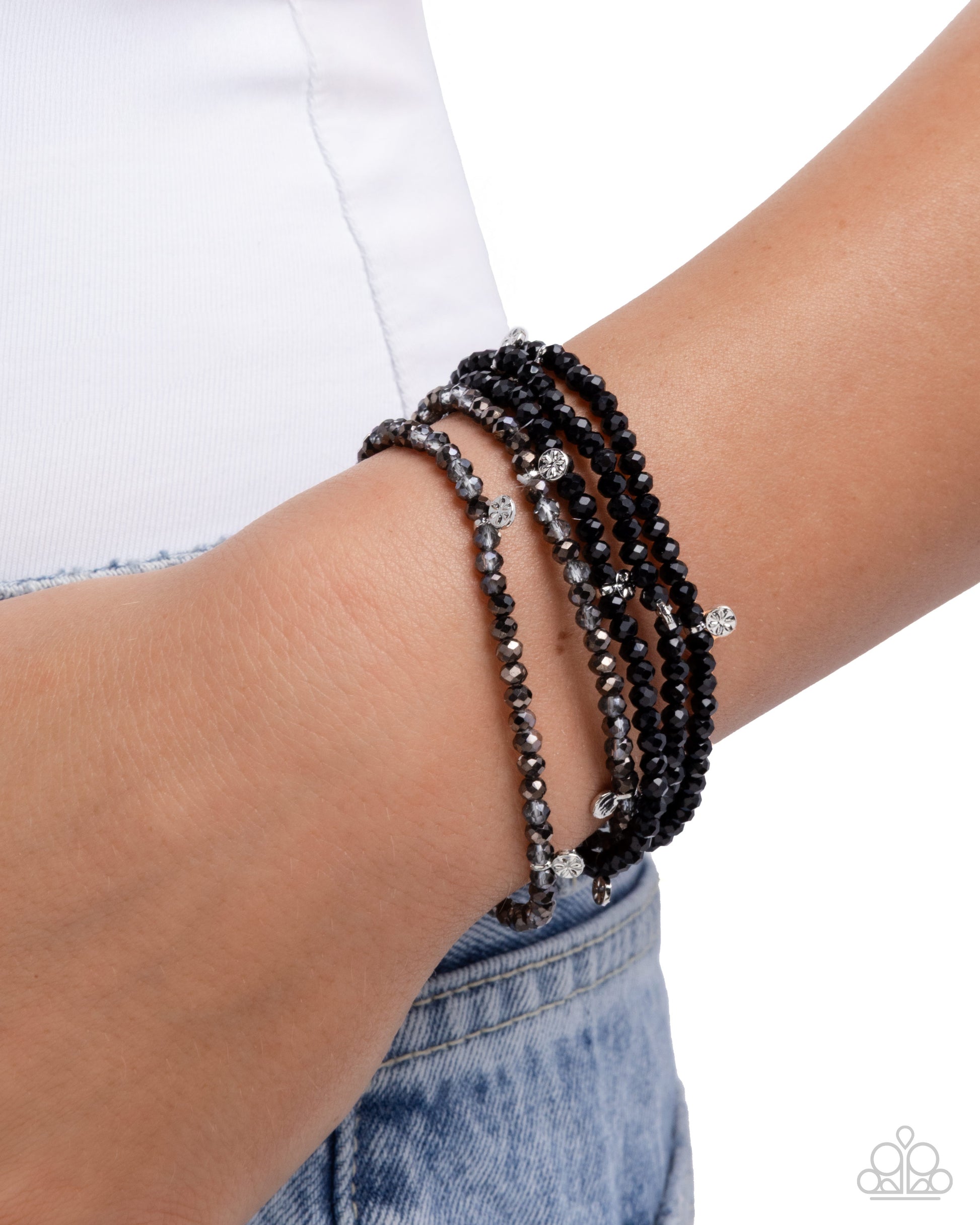 Multiple black beaded bracelets on a wrist with a white background