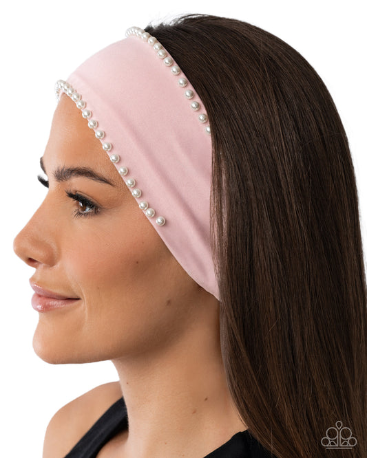 Pink headband with pearl accents worn by a model on a white background