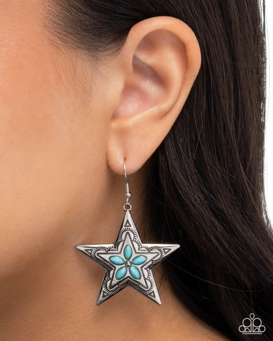 Star-shaped earring with turquoise center worn by a person