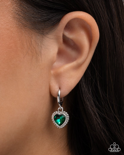 Green heart-shaped earring worn on an ear with dark hair.