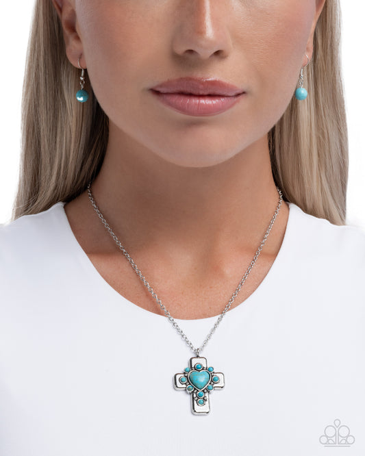 Woman wearing a turquoise cross necklace and earrings on a white background