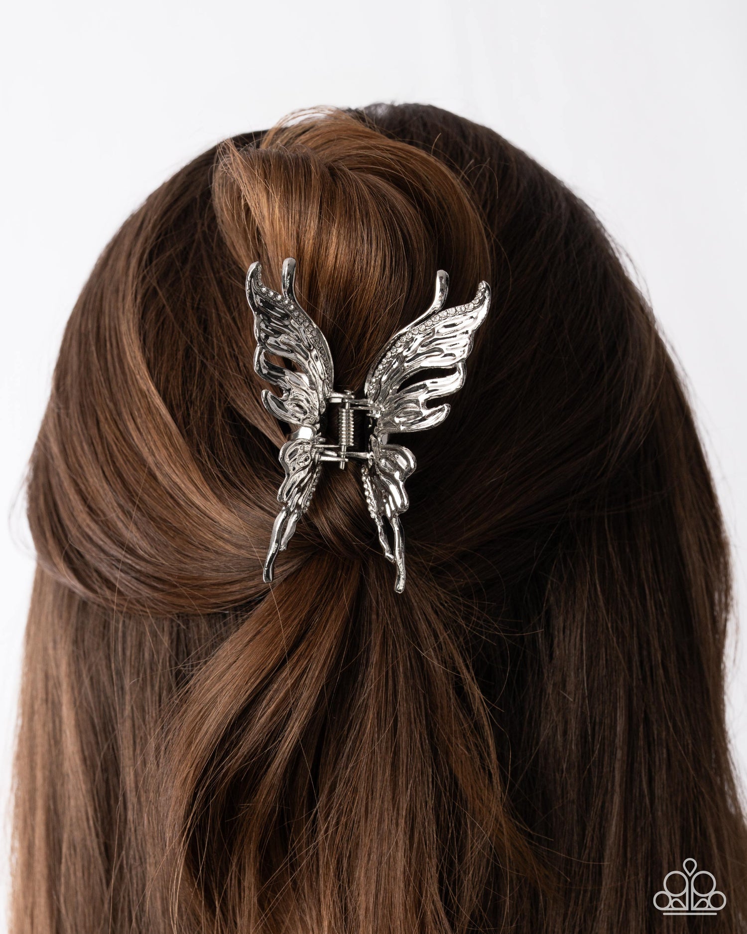 Silver butterfly hair clip on brown hair against a white background