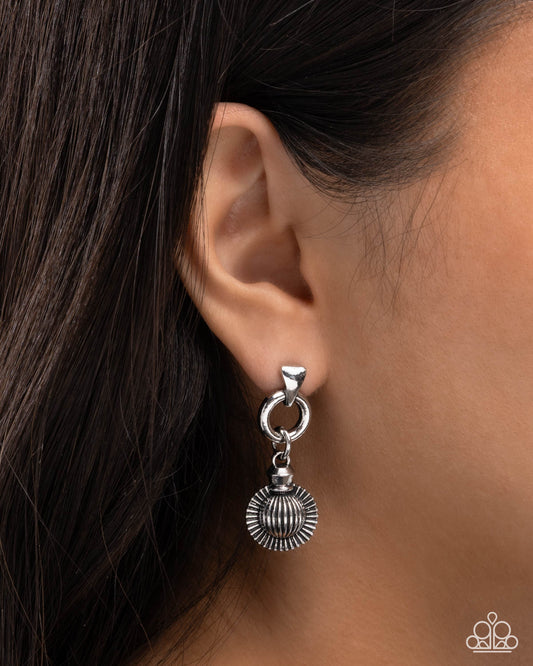 Silver earring worn by a person with dark hair