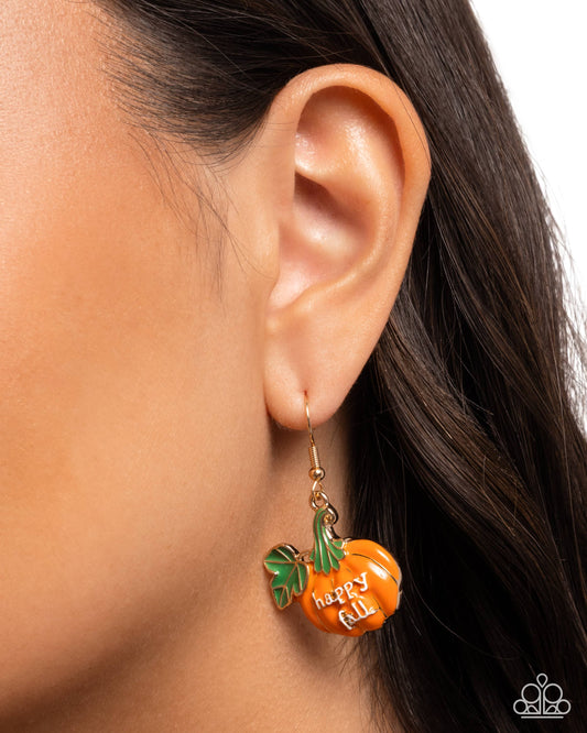 Close-up of an ear wearing a pumpkin-shaped earring with 'Happy Fall' text.