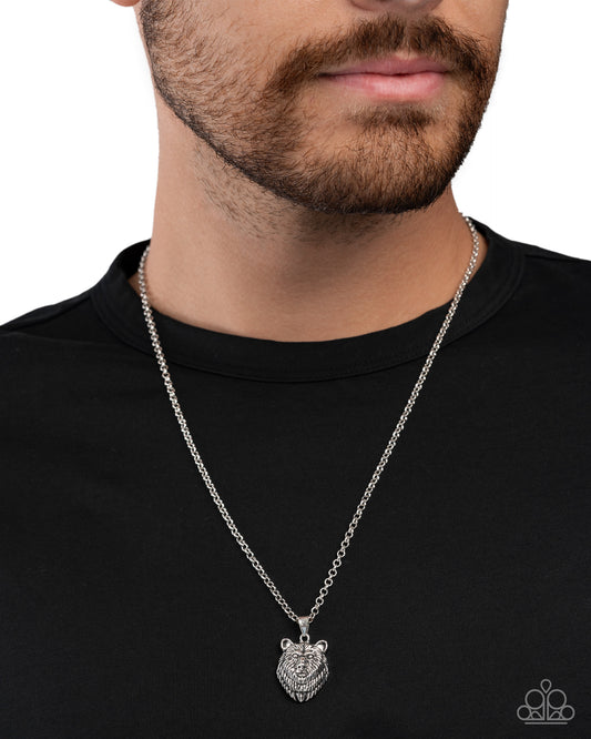Man wearing a silver necklace with a bear pendant on a black shirt