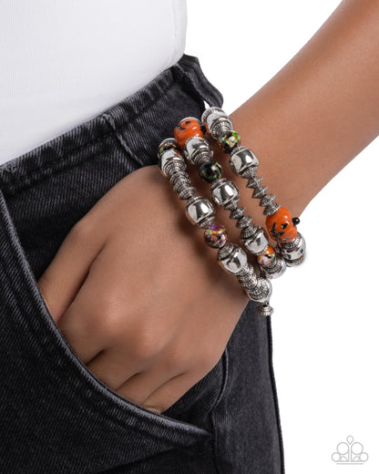 Silver beaded bracelet with orange accents on a wrist against a white background
