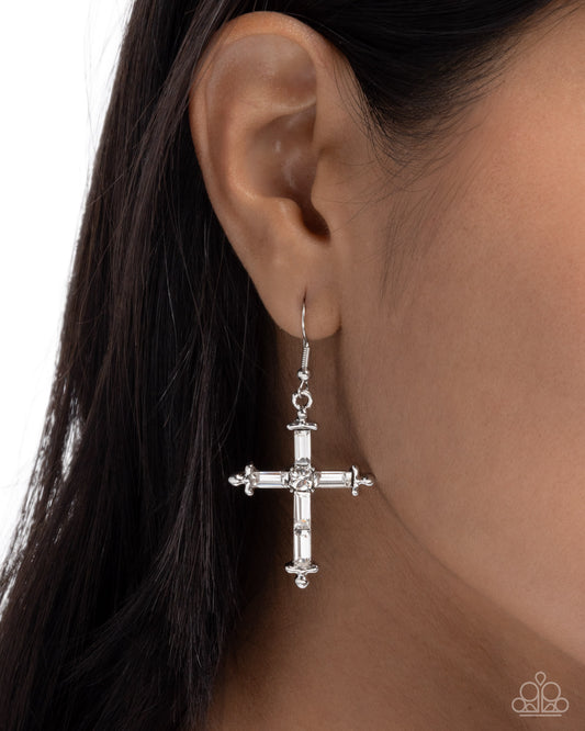 Silver cross earring worn by a person with dark hair on a white background