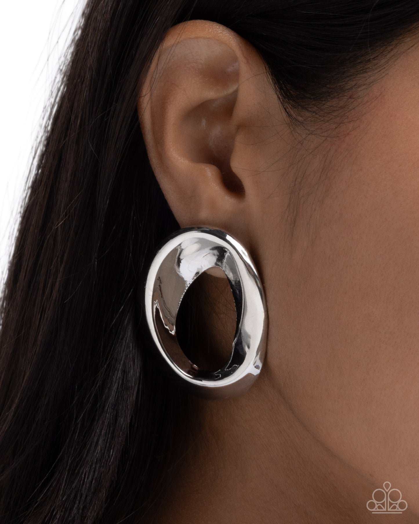 Silver hoop earring worn by a person with dark hair.
