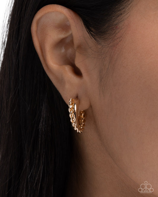Gold hoop earring worn on an ear with dark hair.