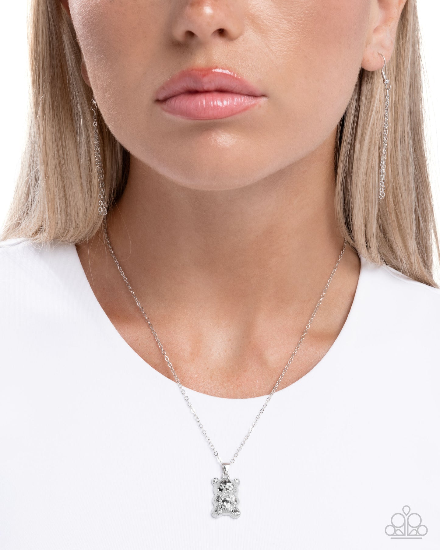Close-up of a woman wearing a silver necklace with a pendant on a plain background