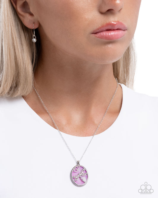 Close-up of a woman wearing a silver necklace with a pink pendant on a white background