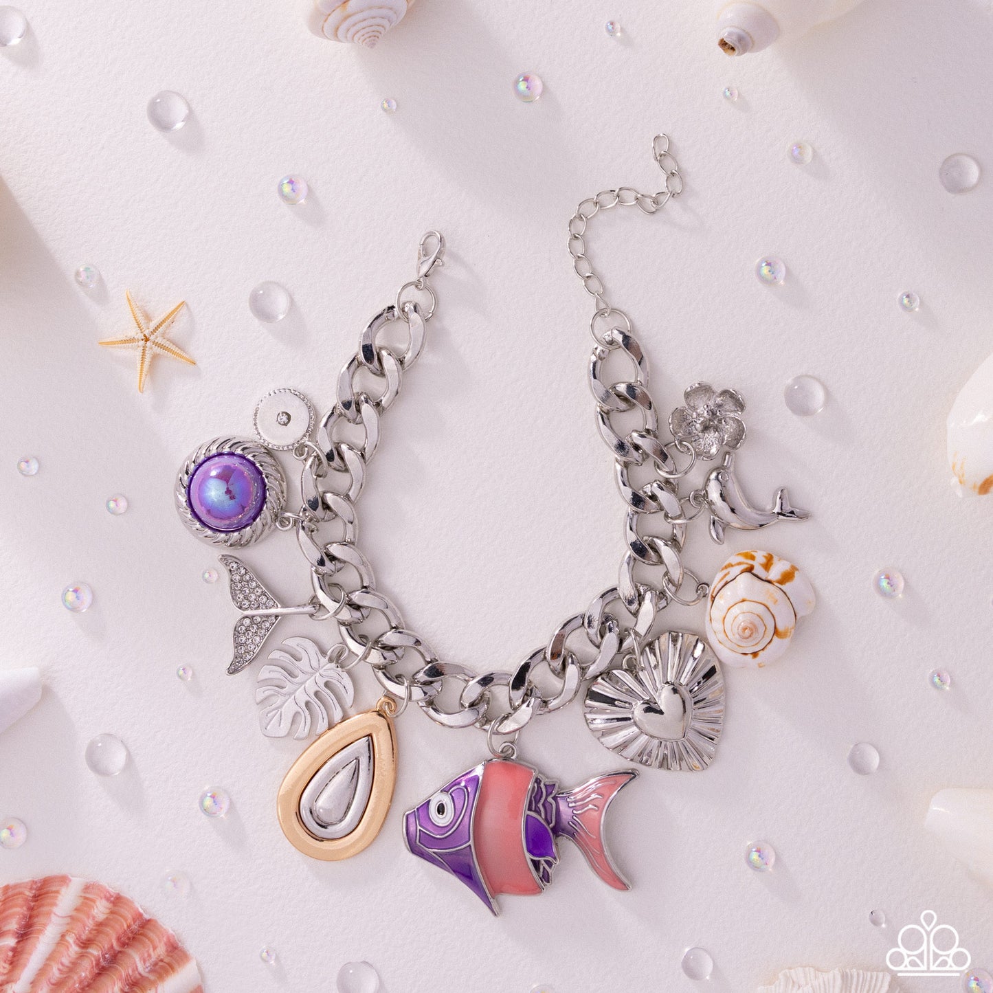 Silver charm bracelet with various charms on a white background with shells and pearls.