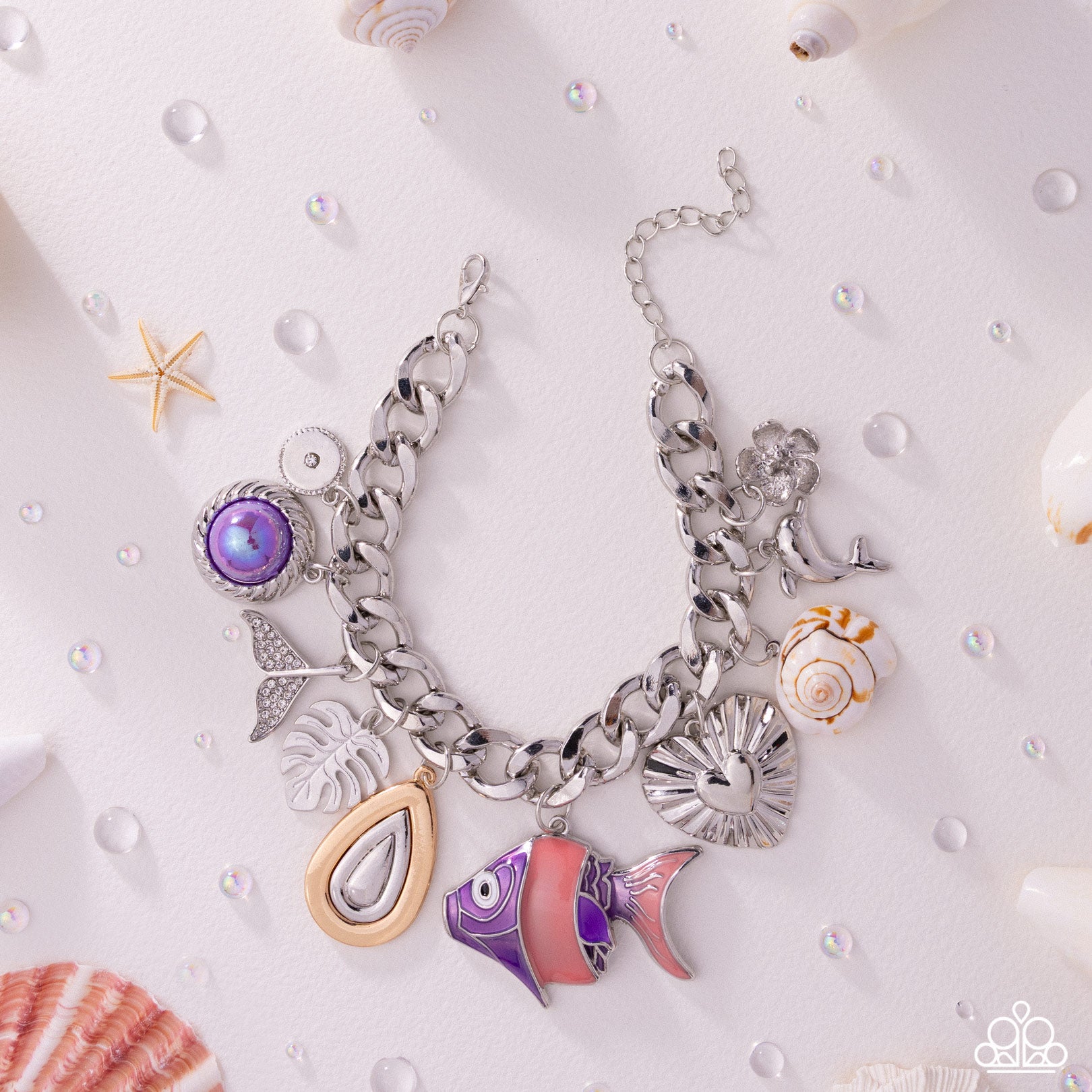 Silver charm bracelet with various charms on a white background with shells and pearls.