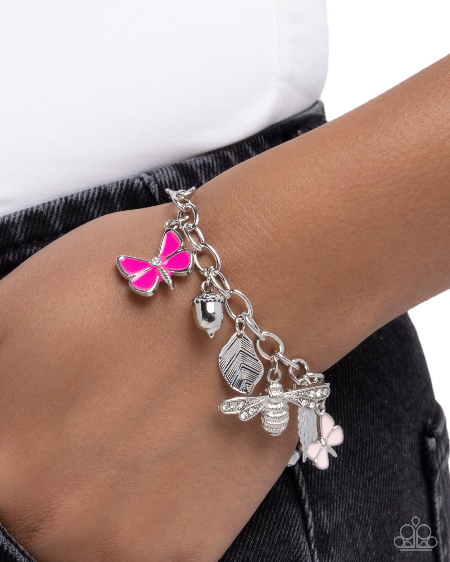 Bracelet with butterfly, acorn, and bee charms on a wrist against a white background