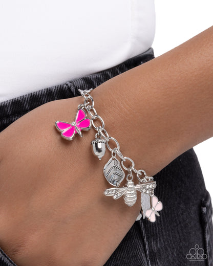 Bracelet with butterfly, acorn, and bee charms on a wrist against a white background