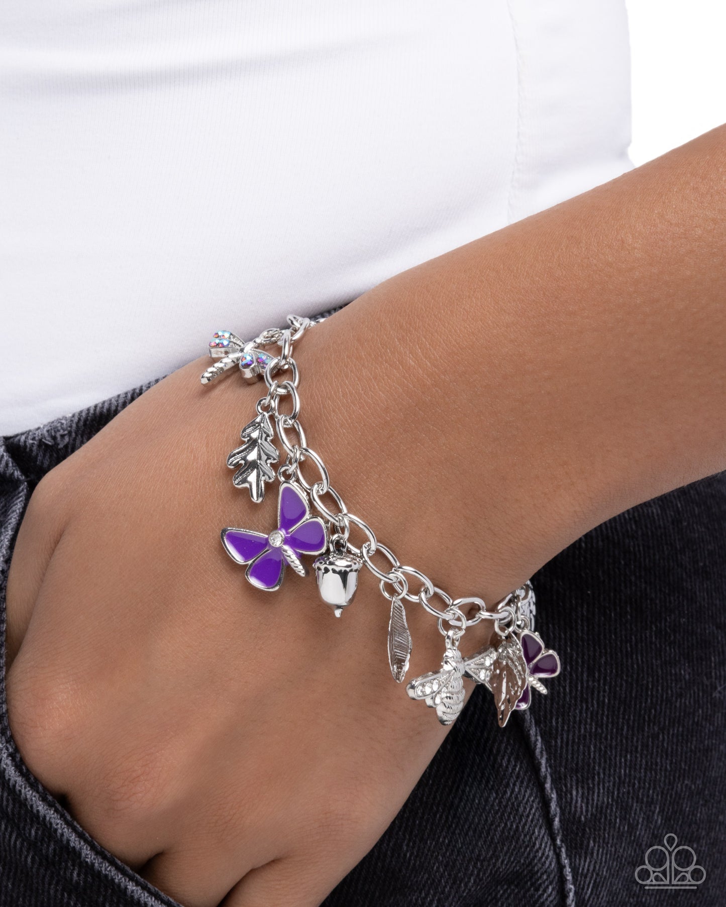 Silver charm bracelet with purple butterfly on wrist against white background