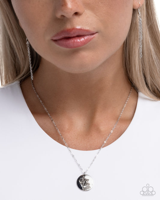 Close-up of a woman wearing a silver necklace with a black pendant on a white background