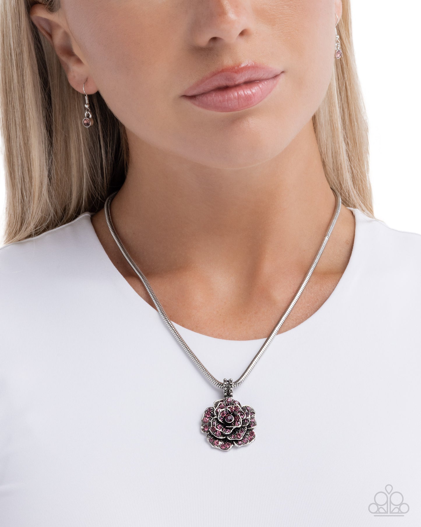 Woman wearing a silver necklace with a floral pendant on a white background