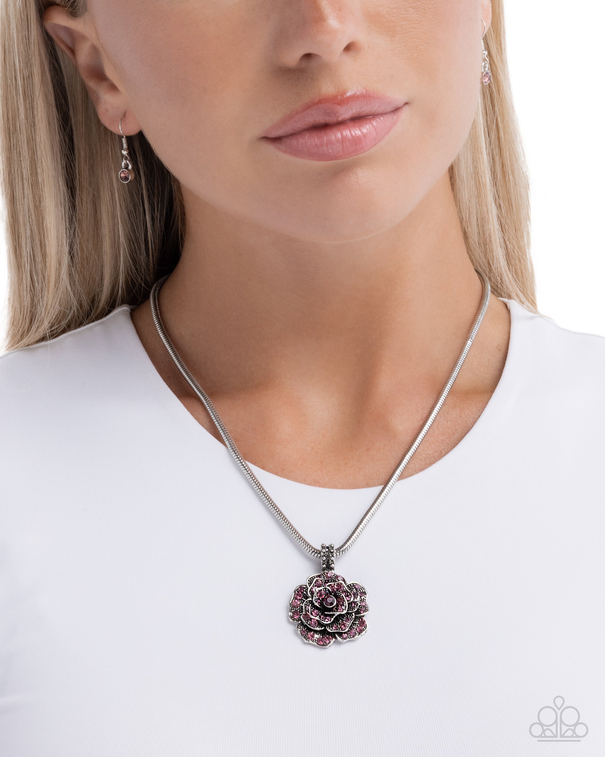 Woman wearing a silver necklace with a floral pendant on a white background