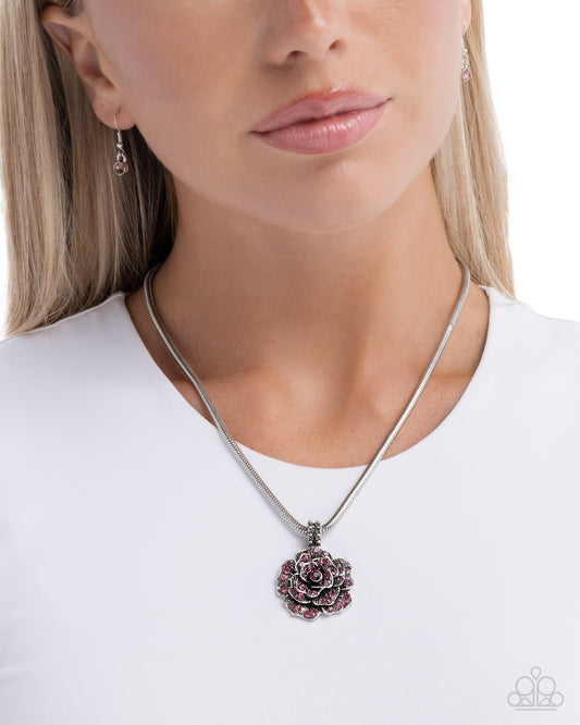 Woman wearing a silver necklace with a floral pendant on a white background