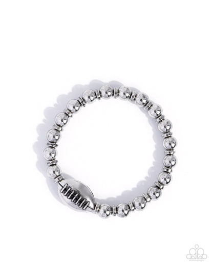 Silver beaded ring with a white band on a white background